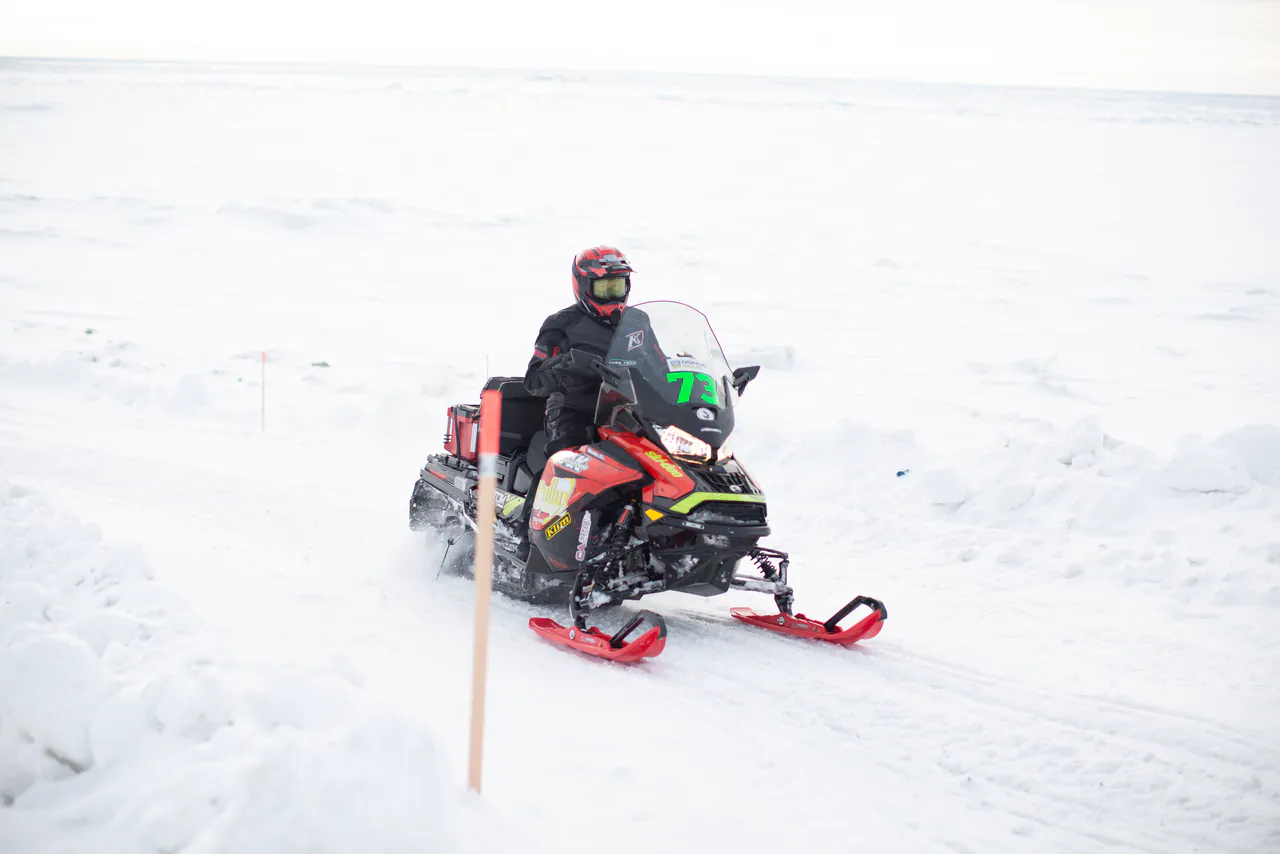 A racer follows a line of trail stakes across featureless white country outside Nome.
