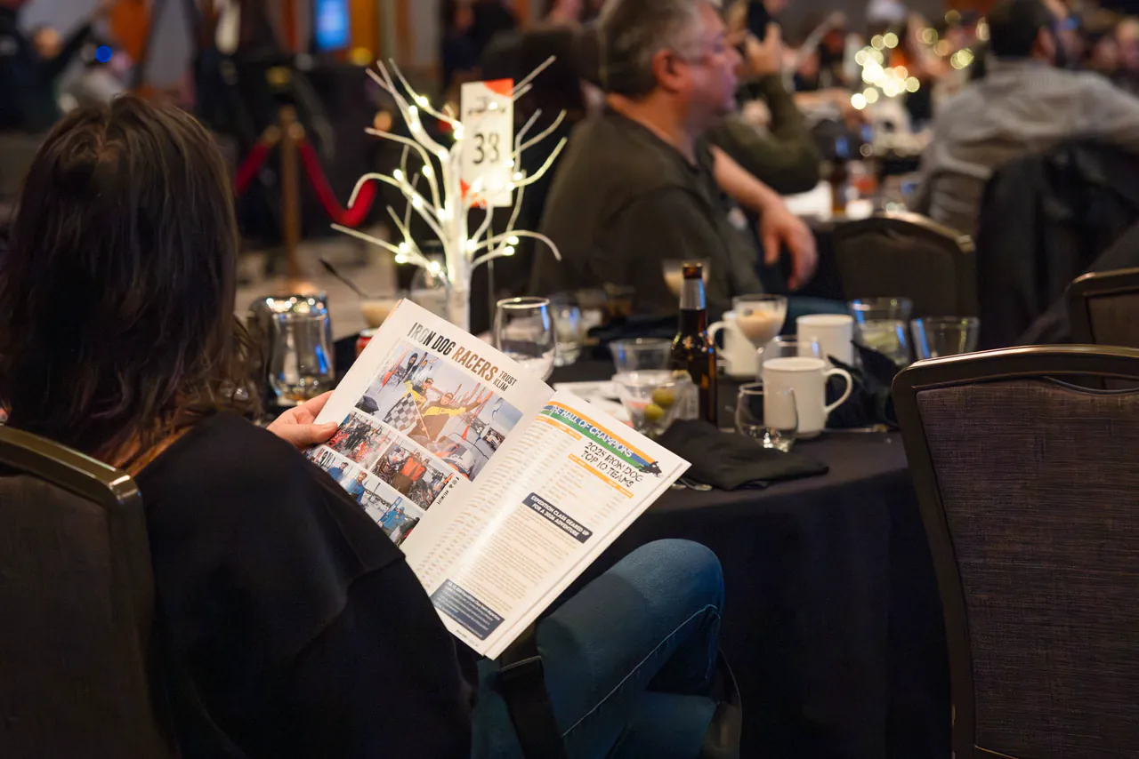 A guest reads the official race guide at a banquet table.