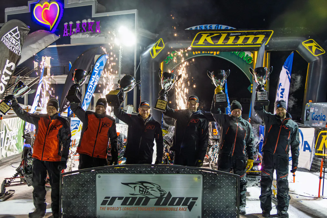 Racers celebrating on the finish stage under sparklers at the end of the race.