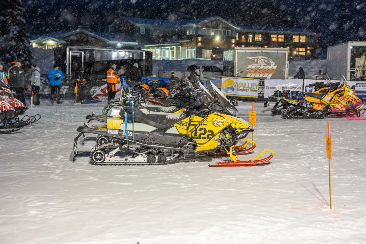 Race sleds parked outside the Big Lake lodge in heavy snowfall before the start.