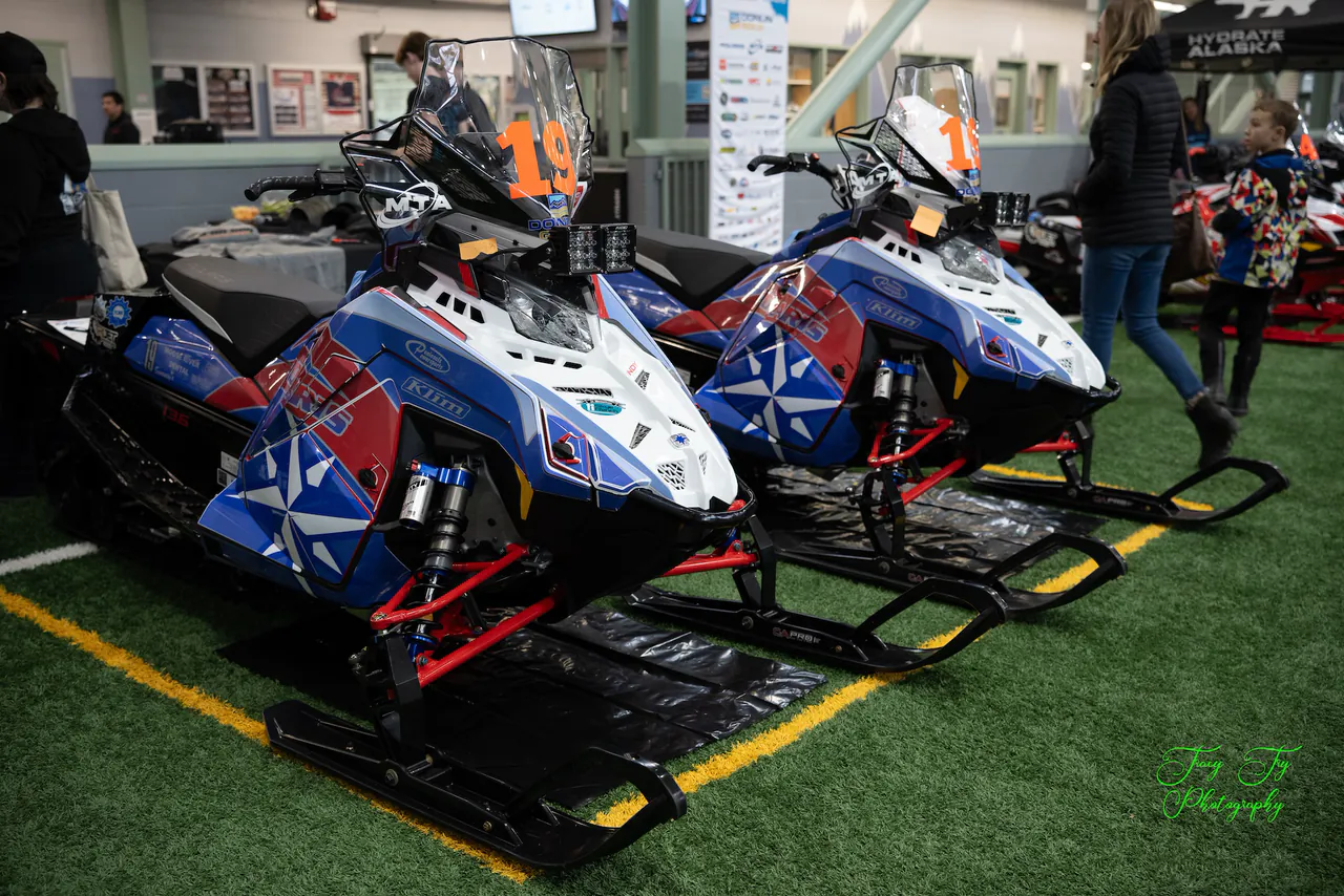 Two sleds wrapped in the Alaska flag design parked side by side at the Menard Center.